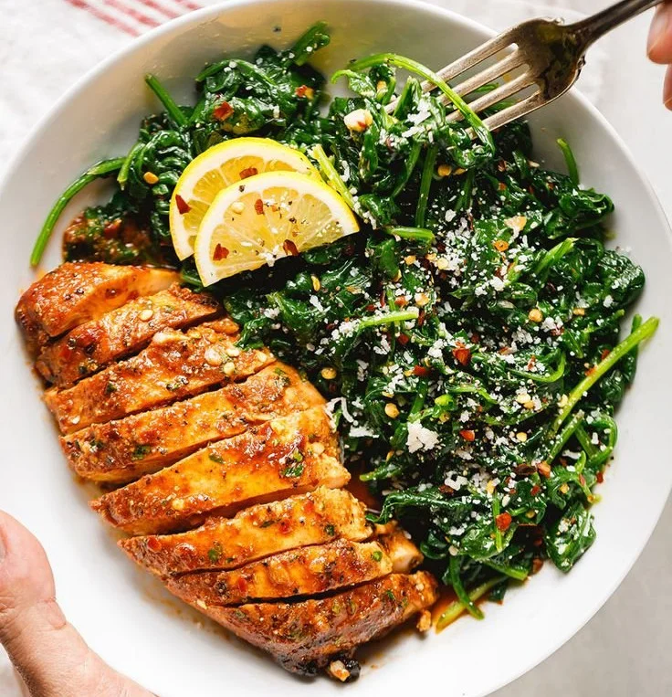 Asado chicken breasts served with sautéed garlic spinach on a plate