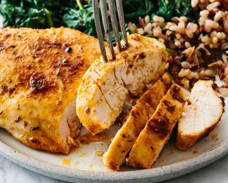 Juicy baked chicken breast served on a plate with herbs