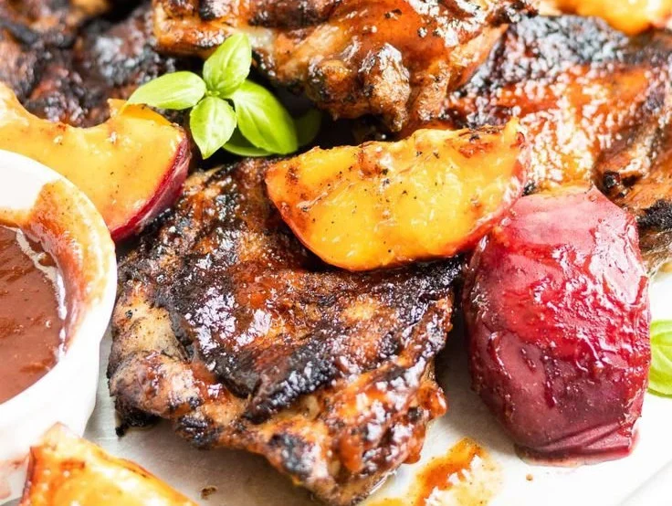 Grilled Bourbon Peach BBQ Chicken garnished with fresh herbs and peach slices