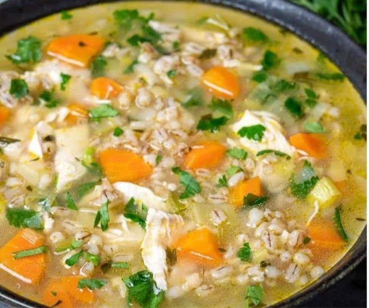Bowl of hearty Chicken Barley Soup garnished with herbs and served with crusty bread.