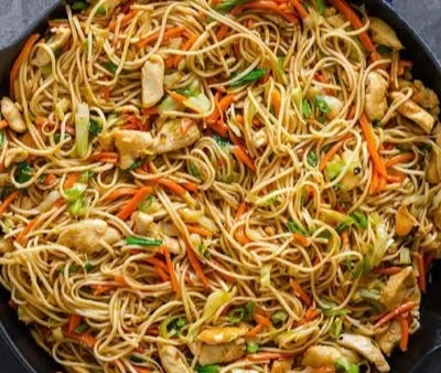 Plate of Chicken Chow Mein topped with vegetables and homemade sauce