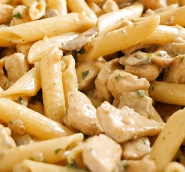 A plate of Chicken Mushroom Pasta garnished with fresh herbs.