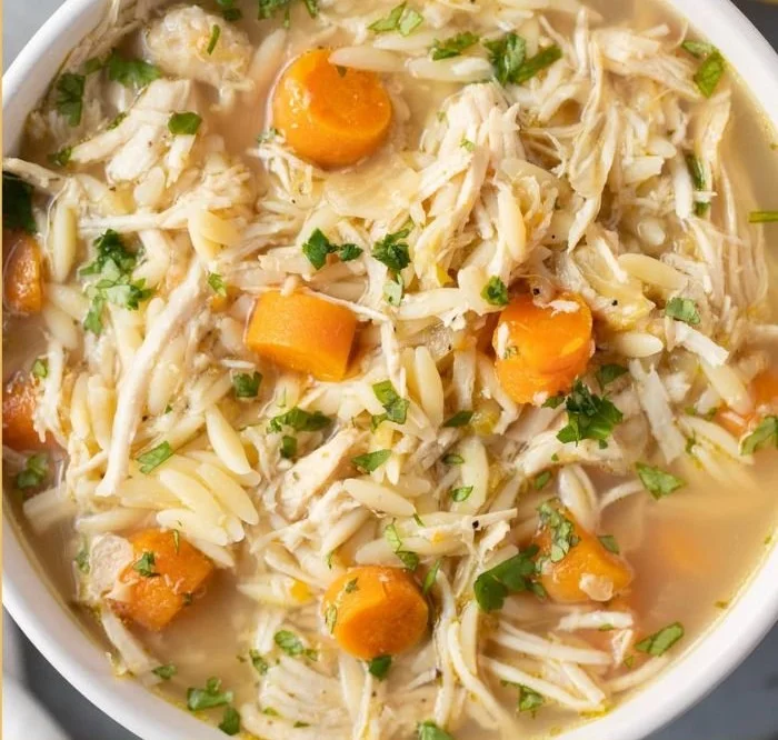 Bowl of Greek Lemon Chicken Soup garnished with lemon and herbs.