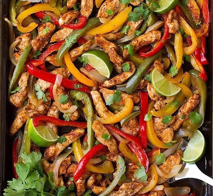Oven-baked chicken fajitas with colorful peppers and onions on a plate.