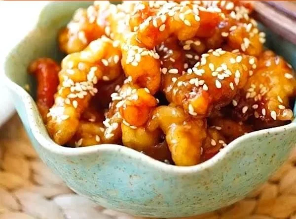 Plate of sesame chicken garnished with sesame seeds and green onions