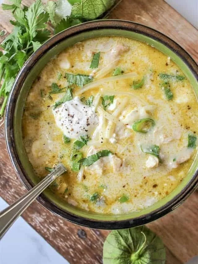 Bowl of slow cooker green enchiladas chicken soup garnished with cilantro and lime.