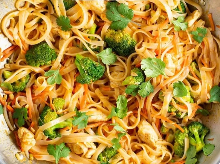 Bowl of Spicy Coconut Curry Chicken served with rice noodles and fresh herbs