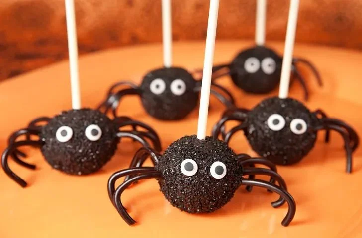 Festive Halloween cake pops decorated with ghoulish designs and vibrant colors