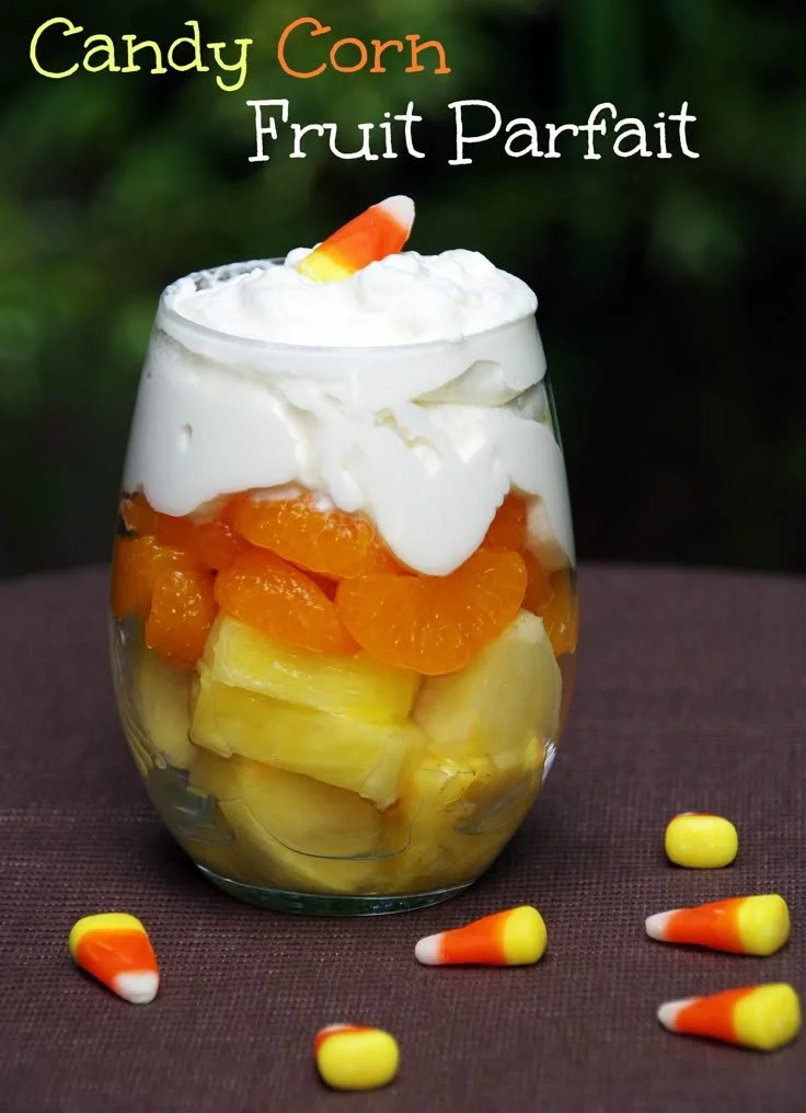 Colorful candy corn parfait layered with fruit and whipped cream.