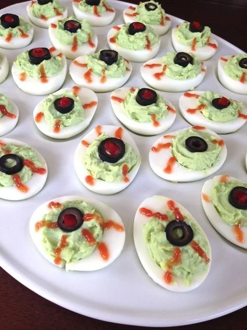 Festive deviled eyeballs recipe served on a Halloween-themed platter.