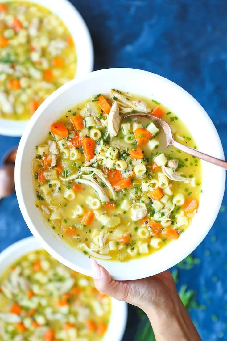 Warm bowl of garlic chicken noodle soup topped with fresh herbs
