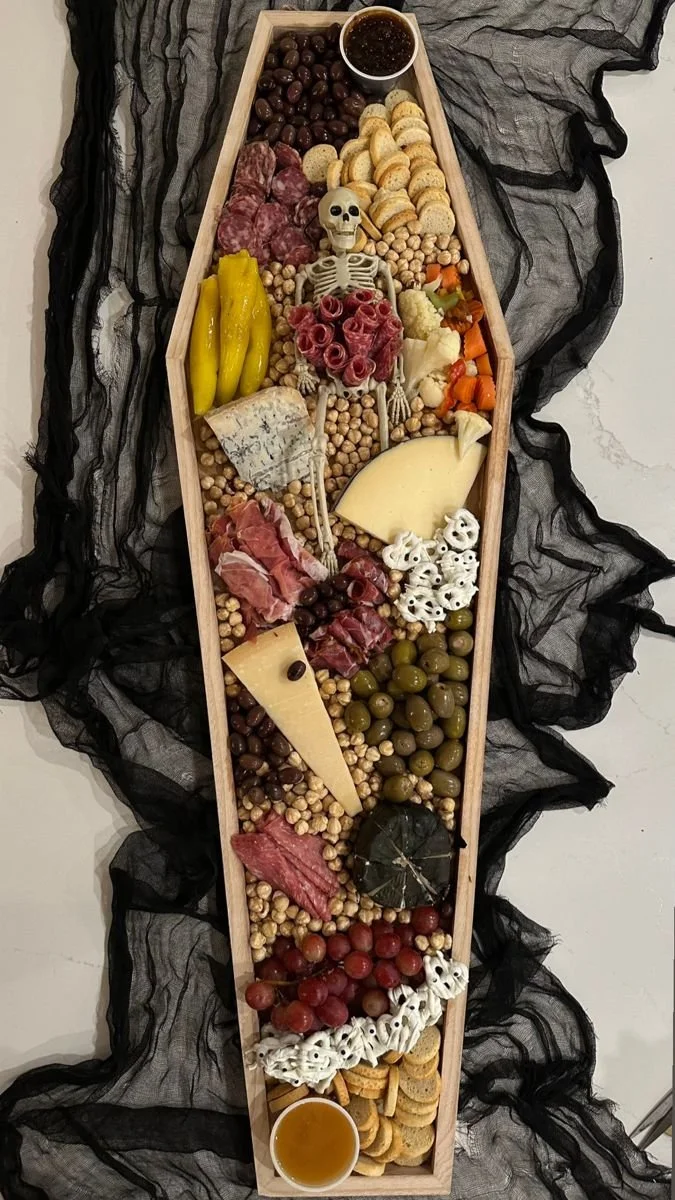 Halloween coffin charcuterie board filled with cheeses and spooky treats.