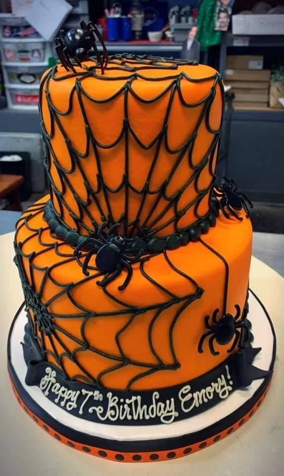 A beautifully decorated tiered spiderweb cake with intricate spiderweb design.
